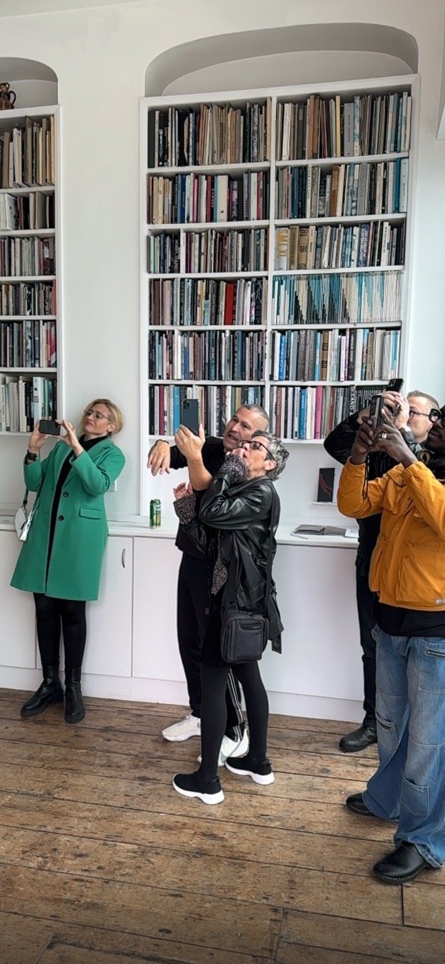 Visitors point phones up at a built-in bookcase in the gallery to view the Encounter augmented-reality work.