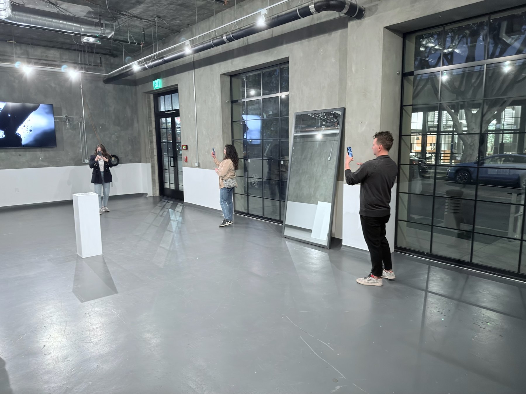 The gallery in West Hollywood: the plinth, the tall mirror and visitors viewing Encounter/Reflection on their phones.
