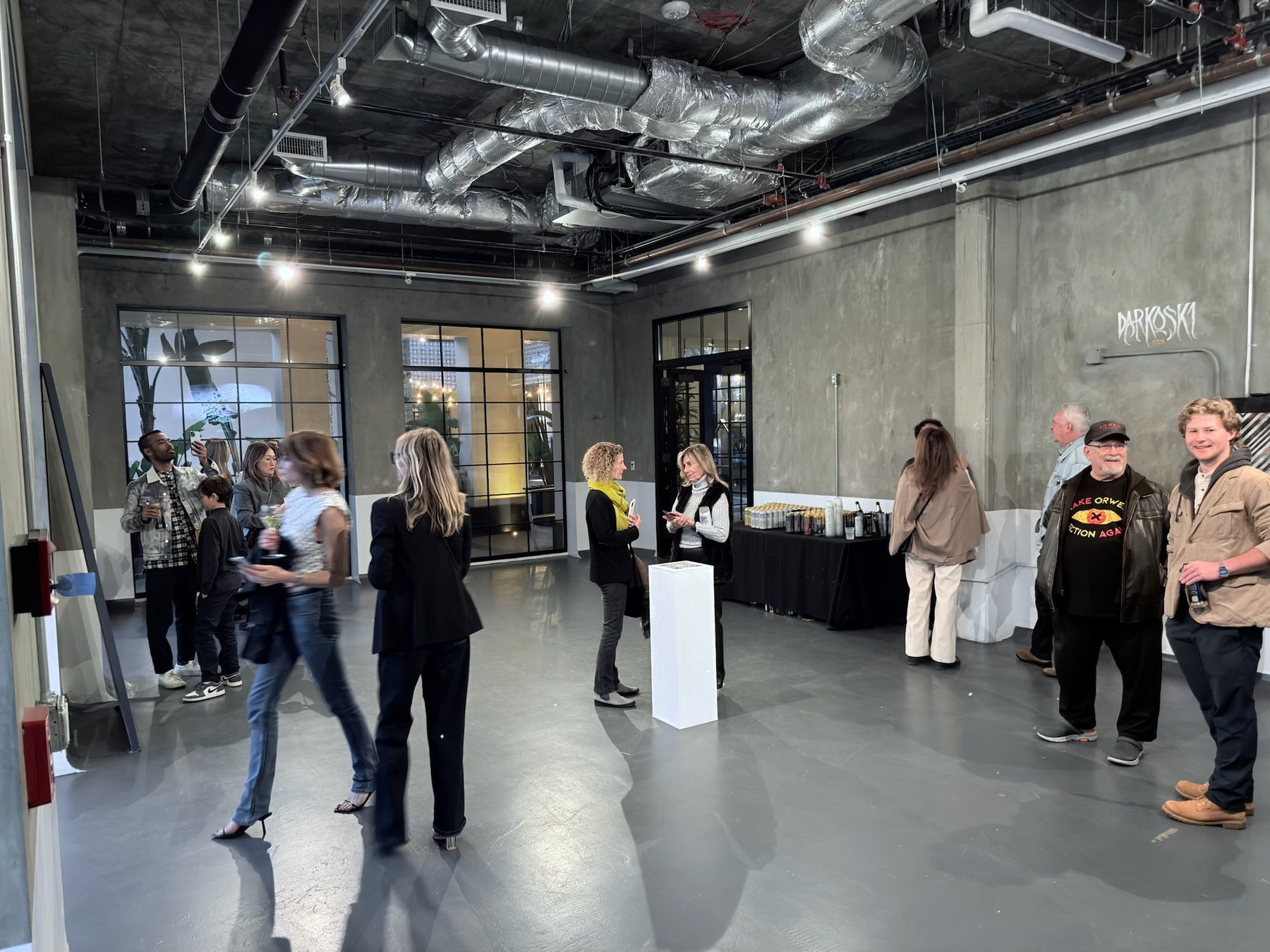 Full view of the room during the opening, with the plinth at the centre and visitors around it.