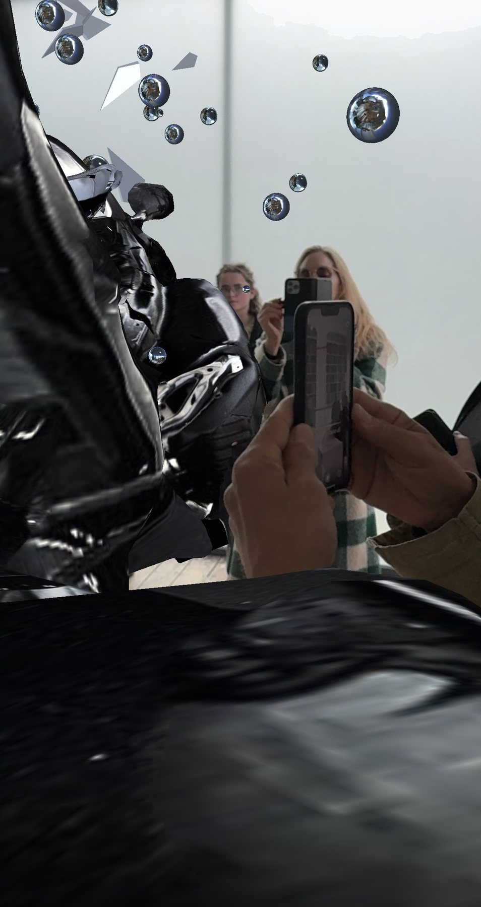 A visitor's hands hold a phone toward the Encounter AR wreck, with other visitors visible in the gallery beyond.