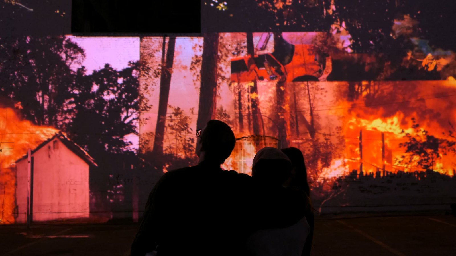 In Case I Forget To Remember: fire projected across a building at night, the audience in silhouette.